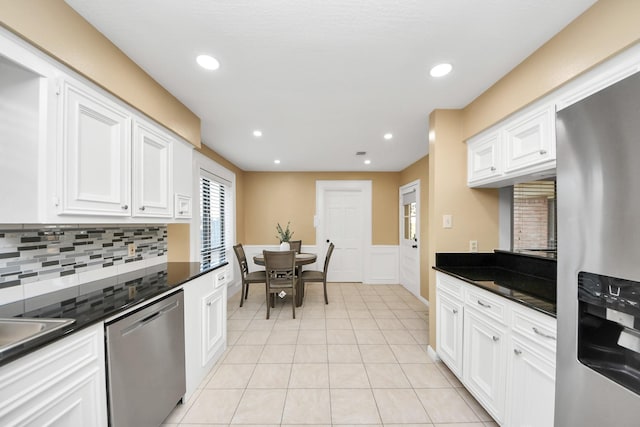 kitchen featuring stainless steel appliances, dark countertops, white cabinetry, and light tile patterned floors