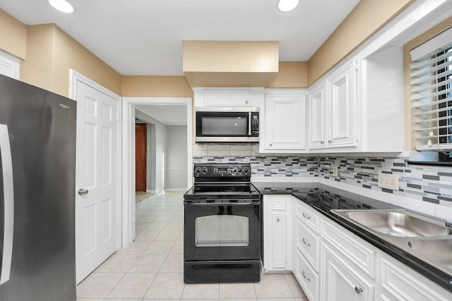 kitchen with dark countertops, backsplash, white cabinetry, light tile patterned flooring, and black appliances