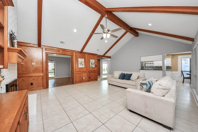 living room featuring a healthy amount of sunlight, ceiling fan, a fireplace, and beamed ceiling