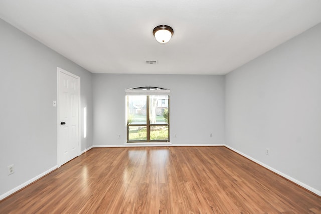 empty room featuring visible vents, baseboards, and wood finished floors