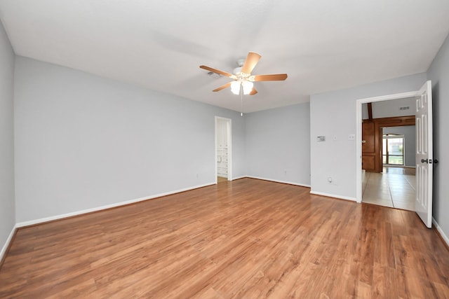 spare room with light wood-type flooring, a ceiling fan, and baseboards