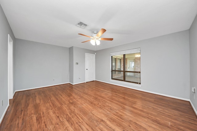 empty room featuring a ceiling fan, baseboards, visible vents, and wood finished floors