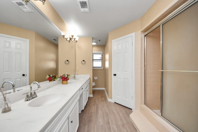 bathroom with double vanity, visible vents, toilet, a sink, and wood finished floors