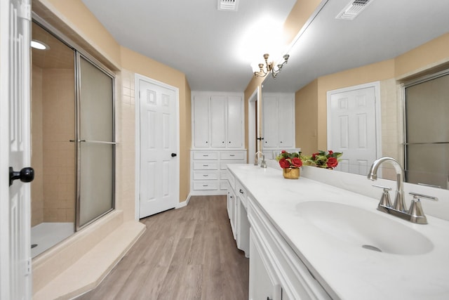 full bathroom with wood finished floors, a stall shower, a sink, and visible vents