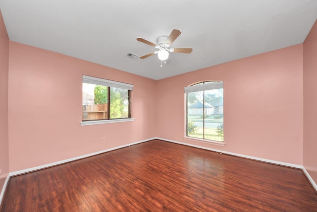 empty room with a healthy amount of sunlight, ceiling fan, baseboards, and wood finished floors