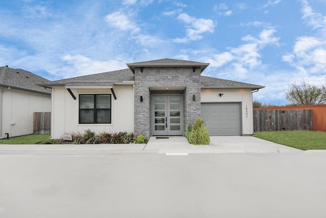 view of front of property featuring an attached garage, a shingled roof, fence, stone siding, and driveway