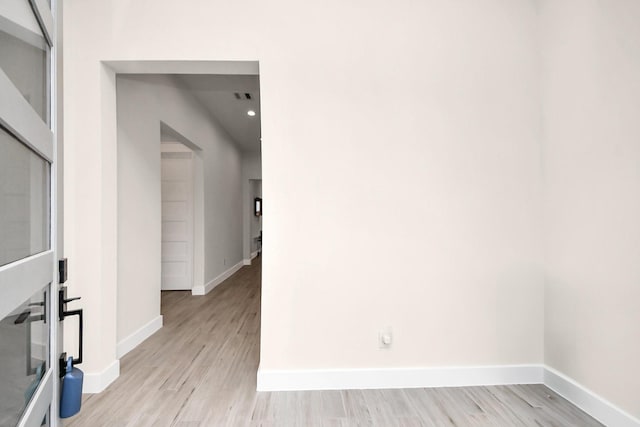 spare room featuring light wood-type flooring, visible vents, and baseboards