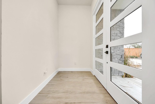 doorway to outside with light wood-type flooring and baseboards