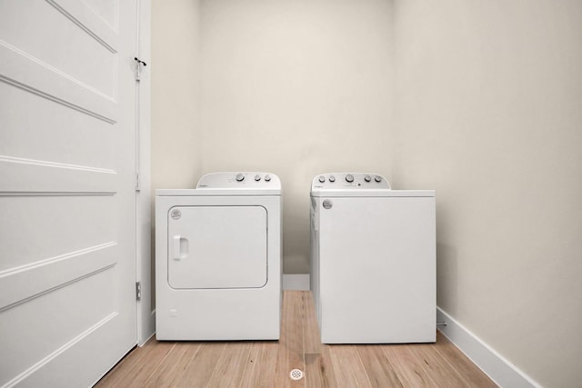 laundry room featuring laundry area, baseboards, light wood finished floors, and independent washer and dryer