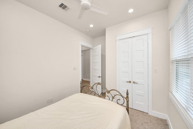 bedroom featuring light colored carpet, a closet, visible vents, and multiple windows