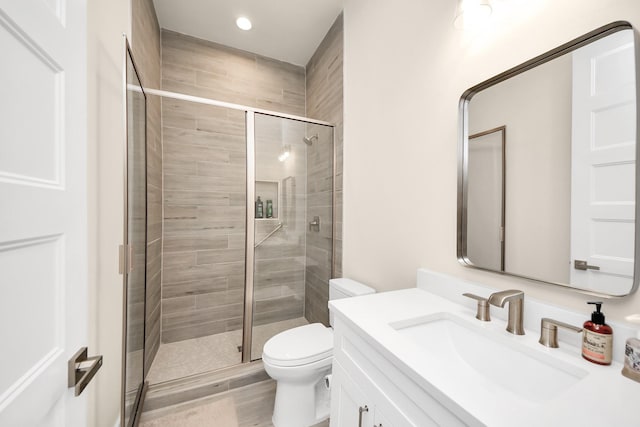 full bathroom featuring recessed lighting, a shower stall, vanity, and toilet