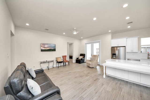 living room featuring french doors, light wood-type flooring, a ceiling fan, and recessed lighting