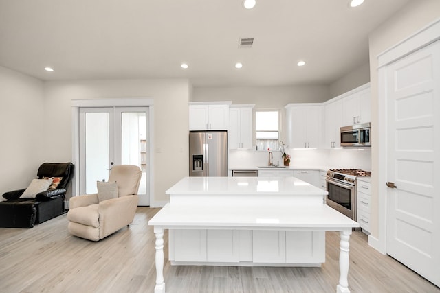 kitchen featuring a sink, stainless steel appliances, a kitchen island, and light countertops