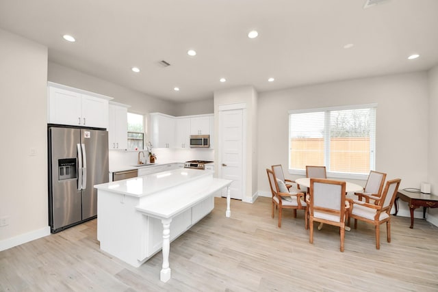 kitchen featuring a sink, white cabinets, light countertops, appliances with stainless steel finishes, and a center island