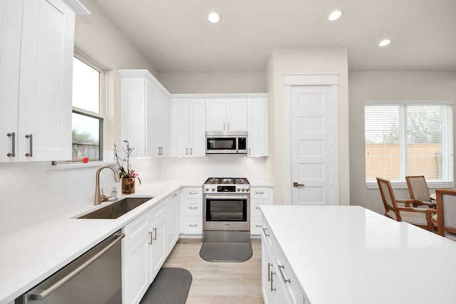 kitchen featuring recessed lighting, a sink, white cabinets, light countertops, and appliances with stainless steel finishes