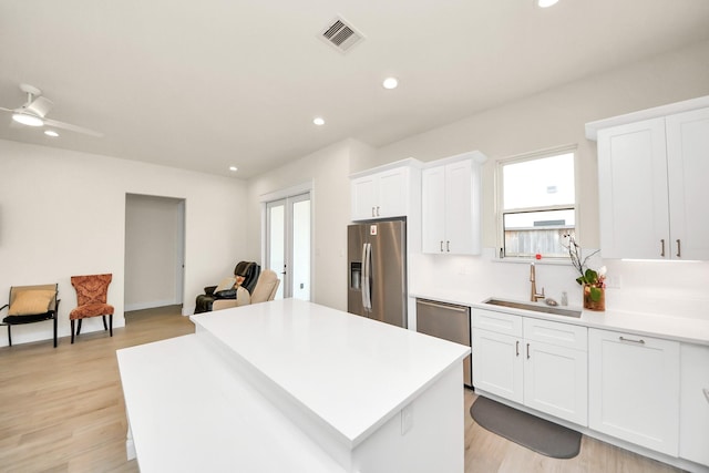 kitchen with stainless steel appliances, light countertops, visible vents, white cabinetry, and a sink