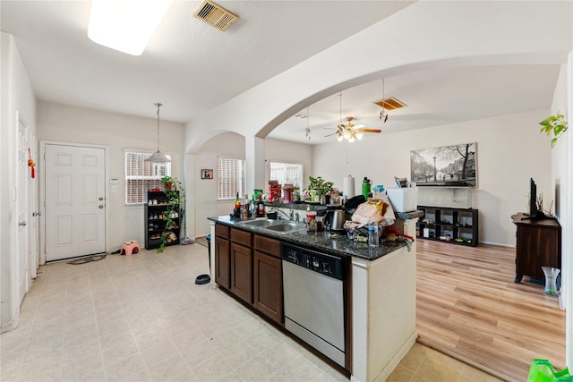 kitchen with visible vents, arched walkways, dishwasher, dark stone countertops, and a sink