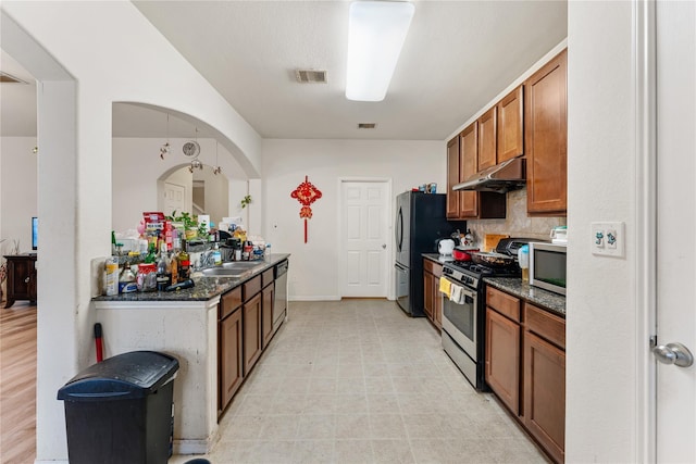 kitchen with under cabinet range hood, a sink, visible vents, appliances with stainless steel finishes, and brown cabinetry