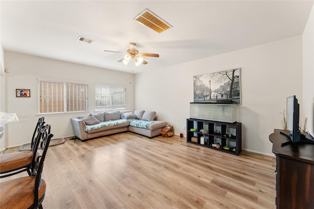 living room with baseboards, light wood-type flooring, visible vents, and a ceiling fan