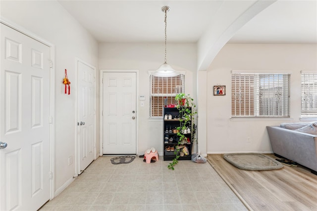 interior space with arched walkways, light wood-style floors, and baseboards