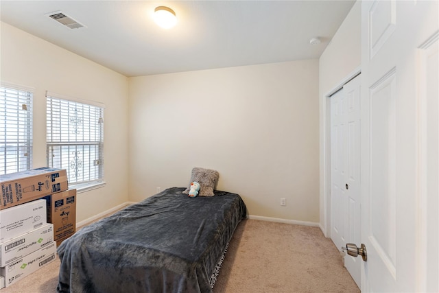 bedroom featuring light carpet, a closet, visible vents, and baseboards