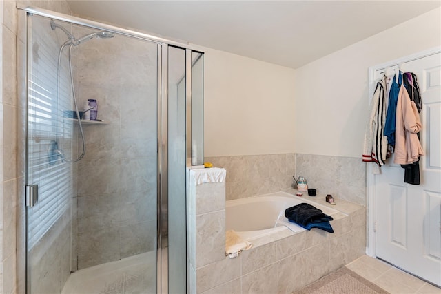 bathroom with a stall shower, tile patterned flooring, and a bath