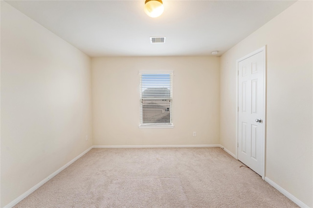 spare room featuring baseboards, visible vents, and light colored carpet