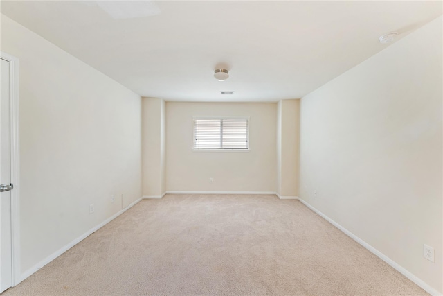 empty room featuring light carpet, visible vents, and baseboards