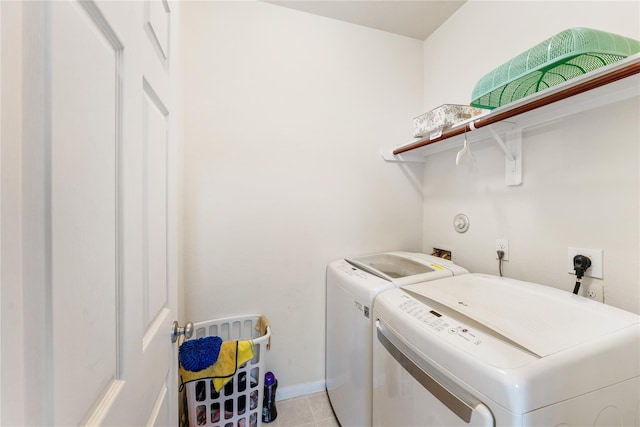 clothes washing area with light tile patterned floors, laundry area, separate washer and dryer, and baseboards