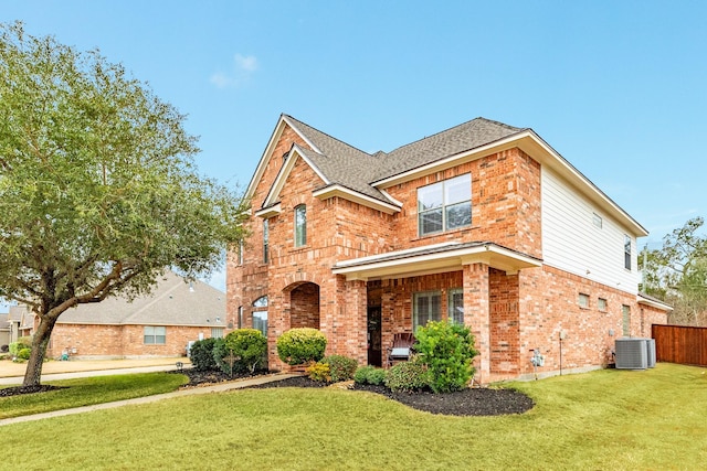 traditional home with central AC, brick siding, a shingled roof, fence, and a front lawn