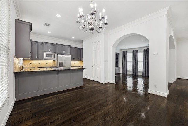 kitchen with pendant lighting, stainless steel appliances, dark countertops, gray cabinets, and visible vents