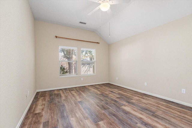 empty room with baseboards, visible vents, ceiling fan, dark wood-type flooring, and vaulted ceiling