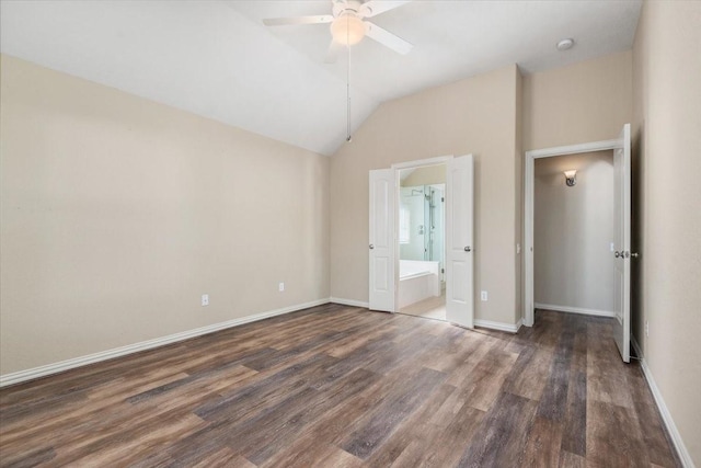 unfurnished bedroom featuring lofted ceiling, ensuite bath, baseboards, and dark wood-style flooring