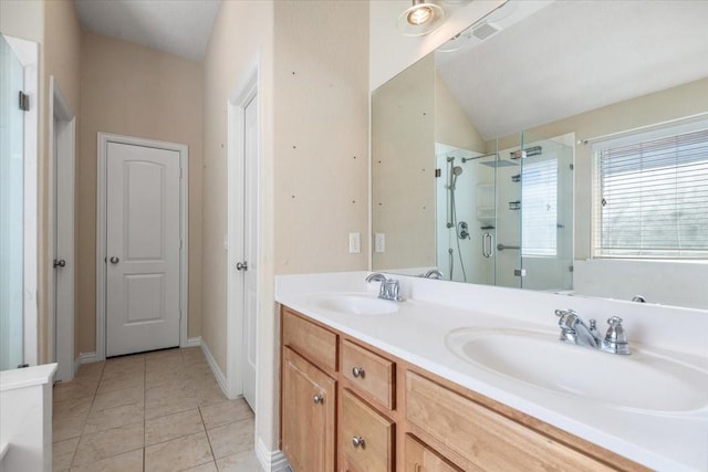 full bathroom with double vanity, a stall shower, a sink, and tile patterned floors