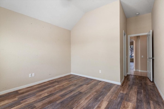 unfurnished room featuring lofted ceiling, dark wood finished floors, and baseboards