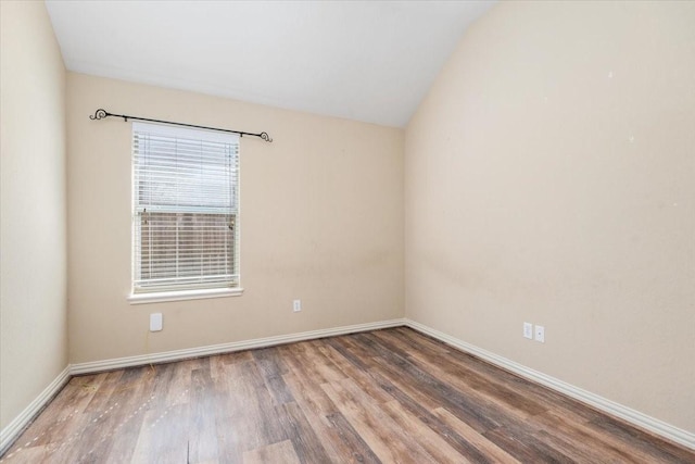 unfurnished room featuring baseboards, vaulted ceiling, and wood finished floors