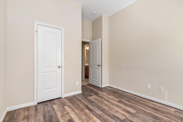 unfurnished bedroom with baseboards and dark wood-type flooring