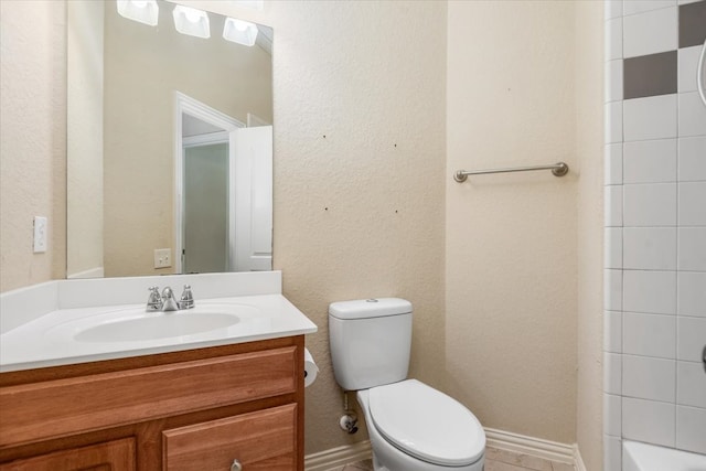 bathroom with a bathtub, a textured wall, toilet, vanity, and baseboards