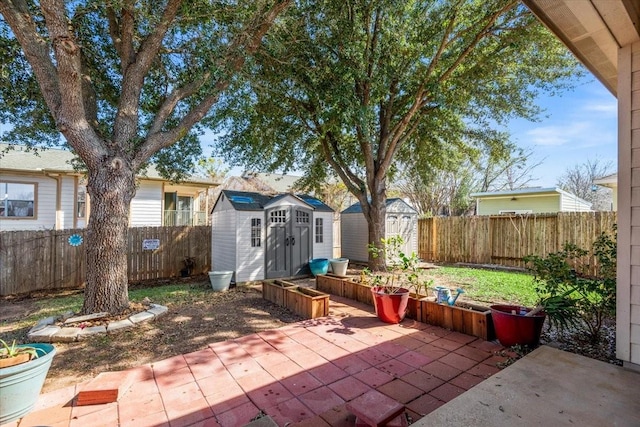 view of patio with a storage shed, a fenced backyard, and an outbuilding