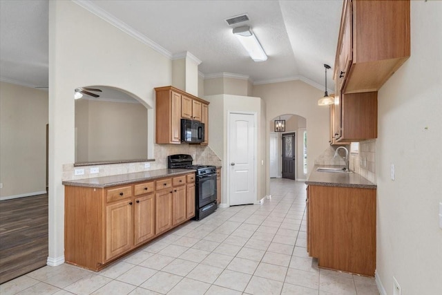 kitchen with visible vents, arched walkways, vaulted ceiling, black appliances, and a sink