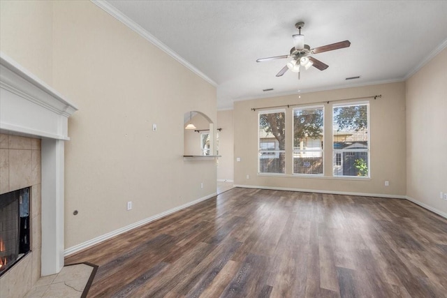 unfurnished living room with ornamental molding, wood finished floors, a tile fireplace, and baseboards