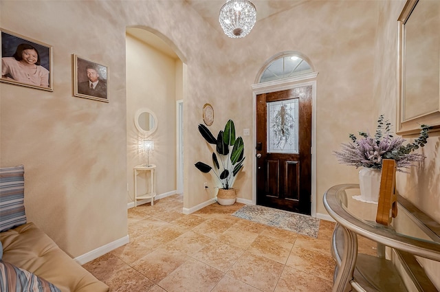 foyer entrance with arched walkways, a towering ceiling, and baseboards