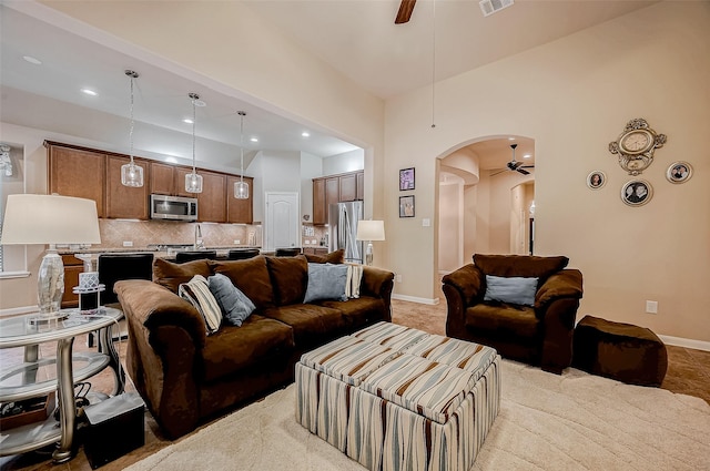 living area with ceiling fan, visible vents, arched walkways, and baseboards