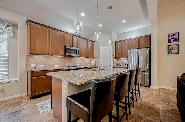 kitchen featuring brown cabinets, a center island with sink, stainless steel appliances, and a kitchen breakfast bar