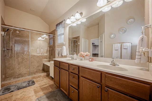 bathroom with lofted ceiling, a sink, a shower stall, and double vanity