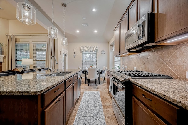 kitchen featuring a sink, visible vents, appliances with stainless steel finishes, a center island with sink, and pendant lighting