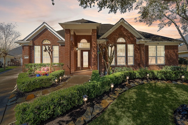 view of front facade featuring brick siding and a yard