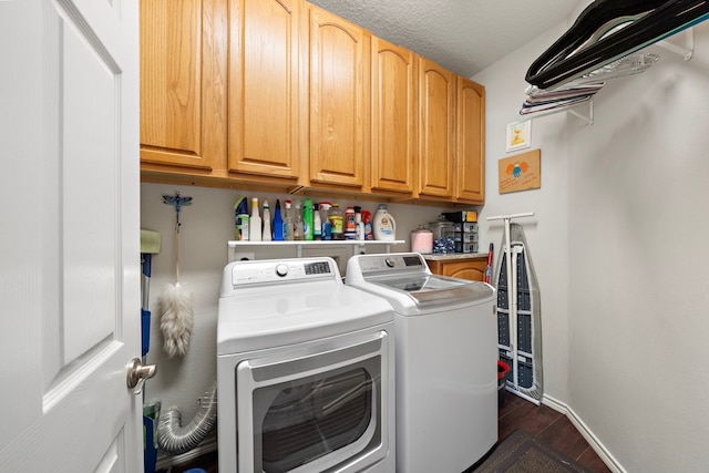 laundry area with a textured ceiling, baseboards, cabinet space, dark wood-style floors, and washer and clothes dryer