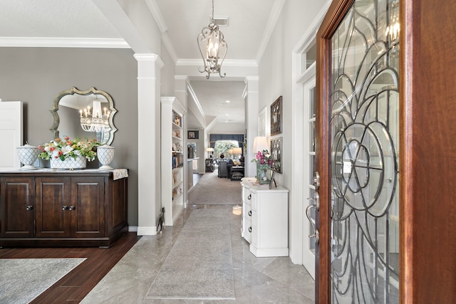 entrance foyer featuring a notable chandelier, visible vents, baseboards, ornamental molding, and decorative columns