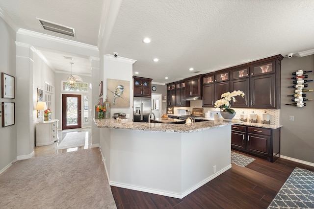 kitchen featuring built in fridge, visible vents, glass insert cabinets, and dark brown cabinets